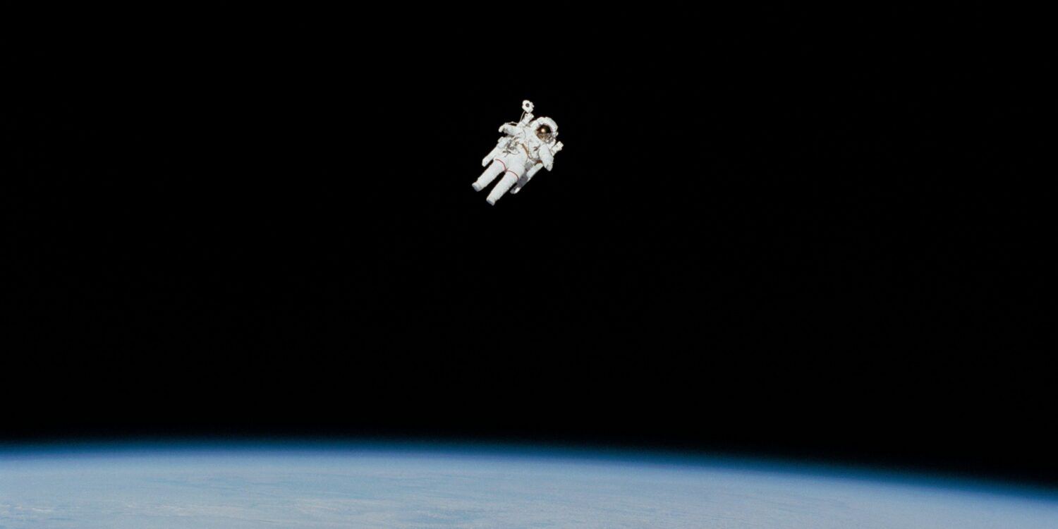 A lone astronaut floating in the vast darkness of space, Earth a distant blue marble in the background